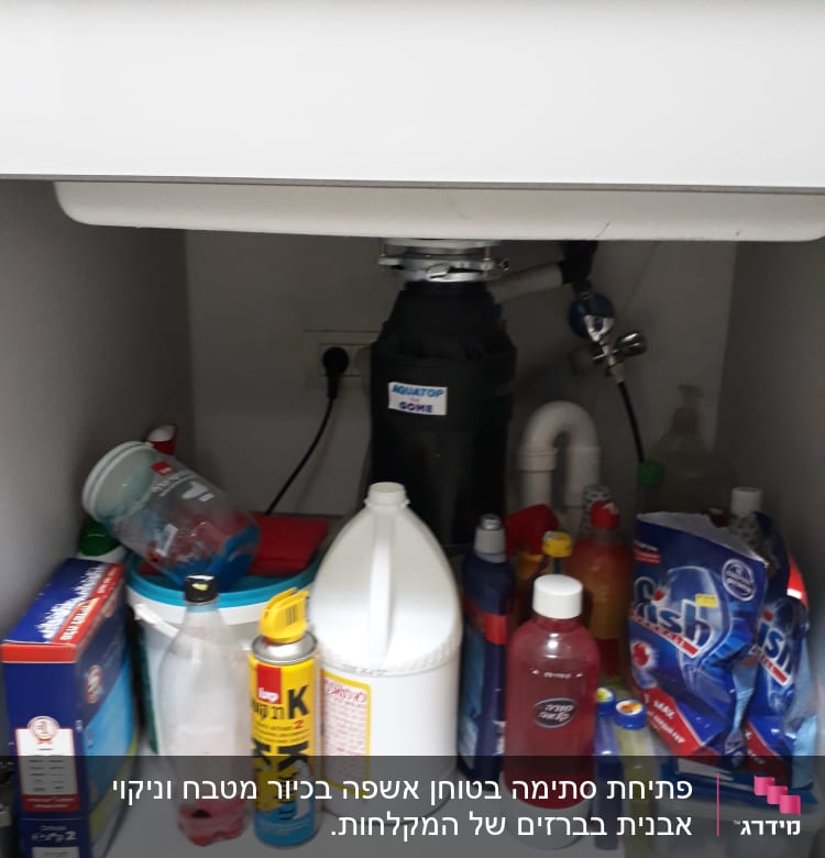 כיור עם צנרת וכלי ניקוי מתחת לארון